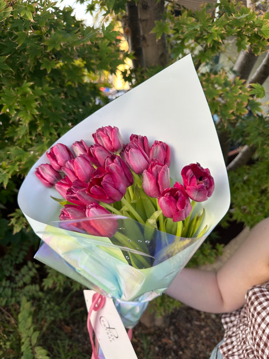 A bunch of pink tulips wrapped in a paper with a floral pattern.